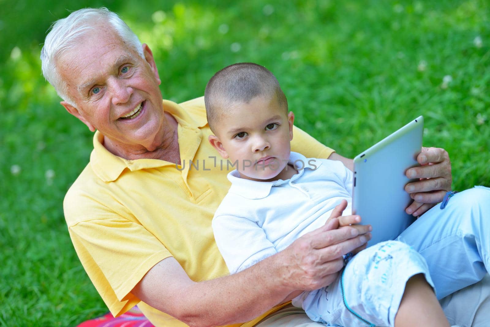 grandfather and child in park using tablet computer