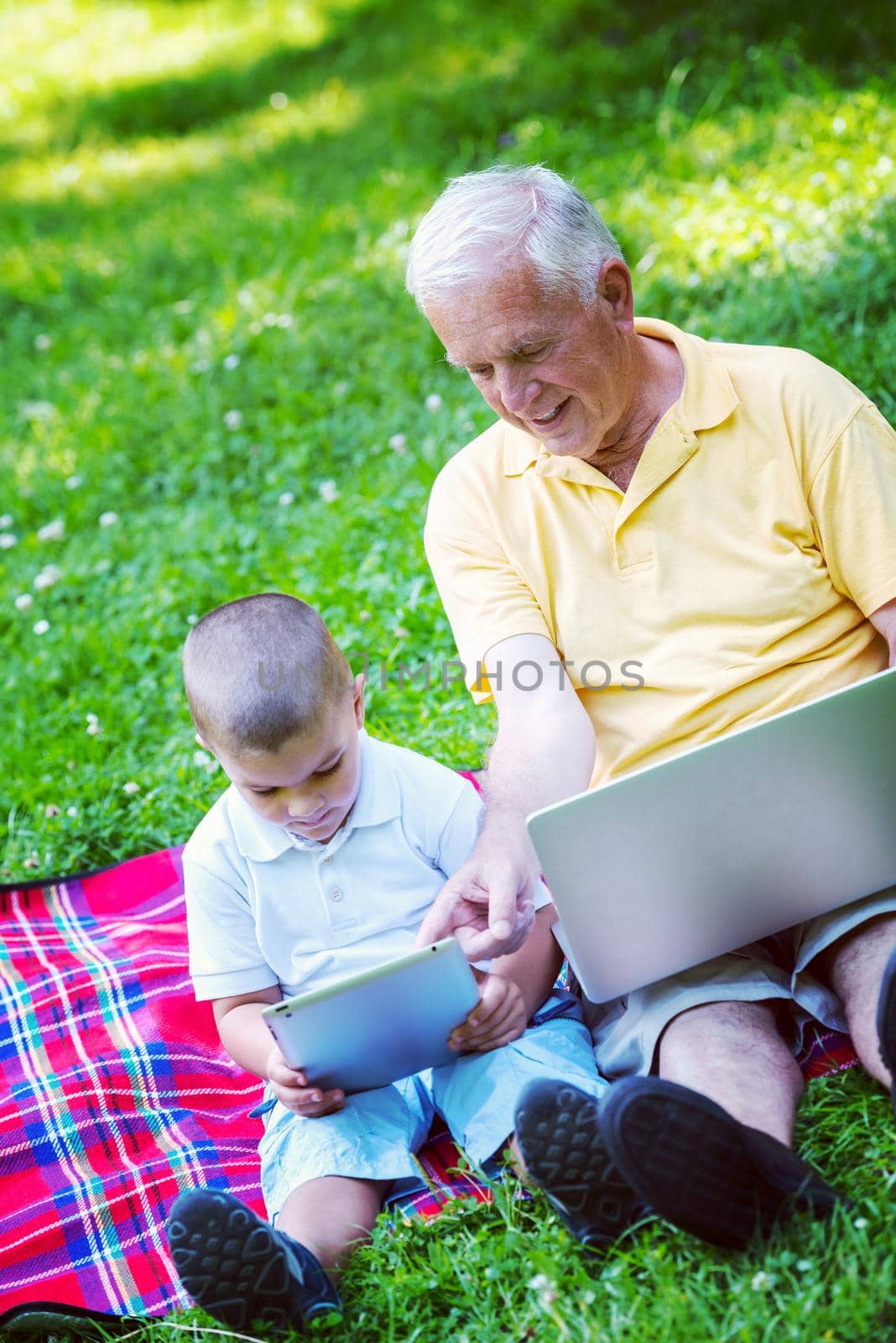 grandfather and child using tablet computer in park