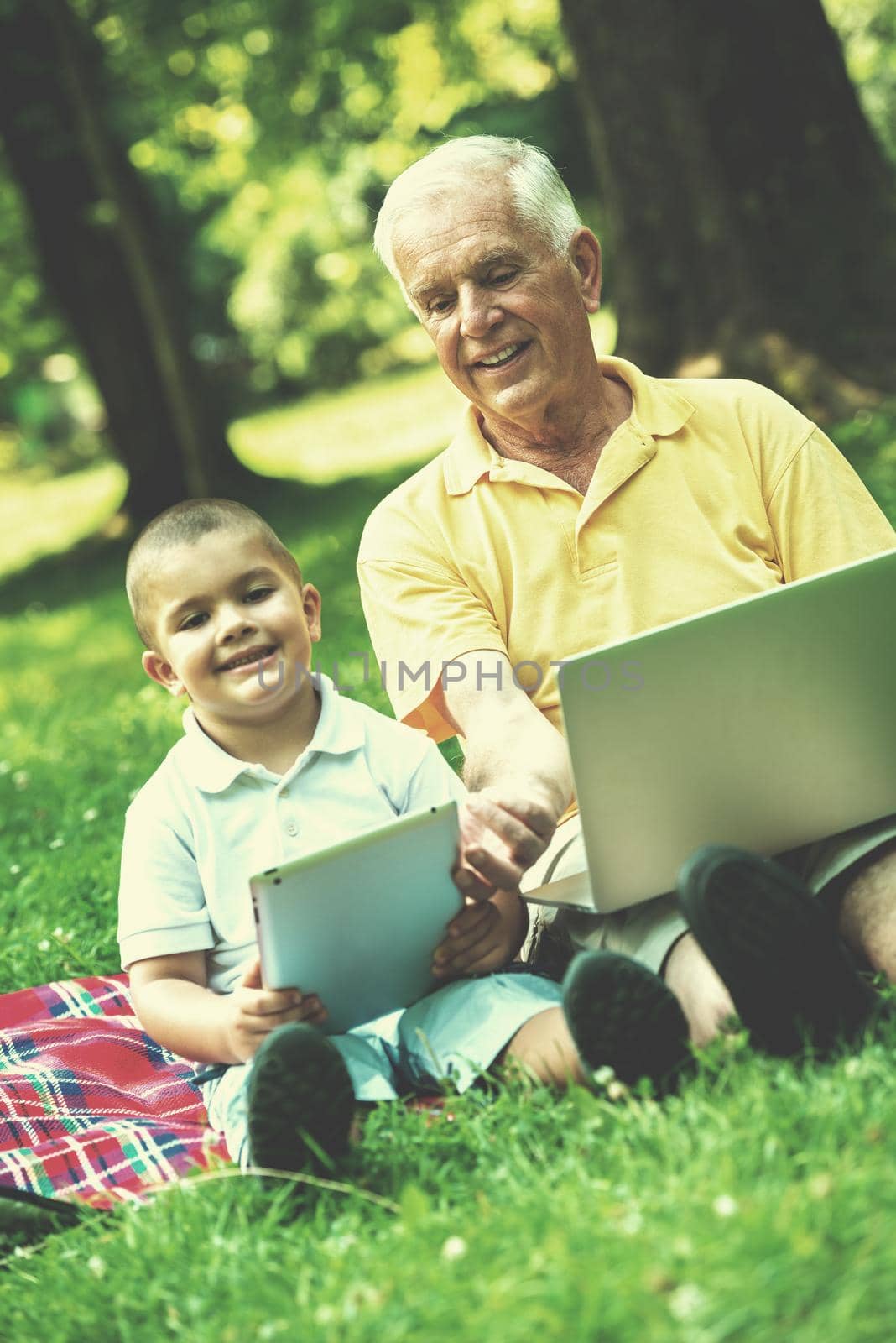 grandfather and child using tablet computer in park