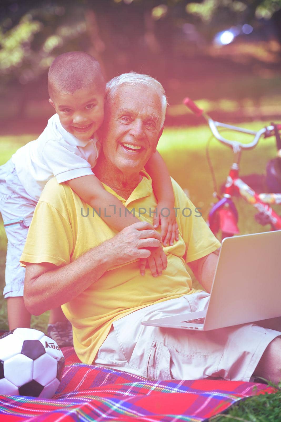 happy elderly senior grandfather and child in park using laptop computer