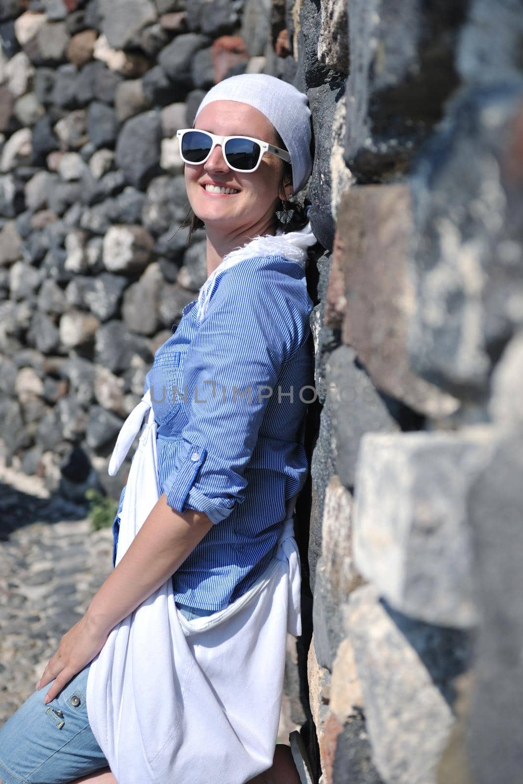 Beautiful young Greek woman in fashion clothes have fun at n the streets of Oia, Santorini, Greece