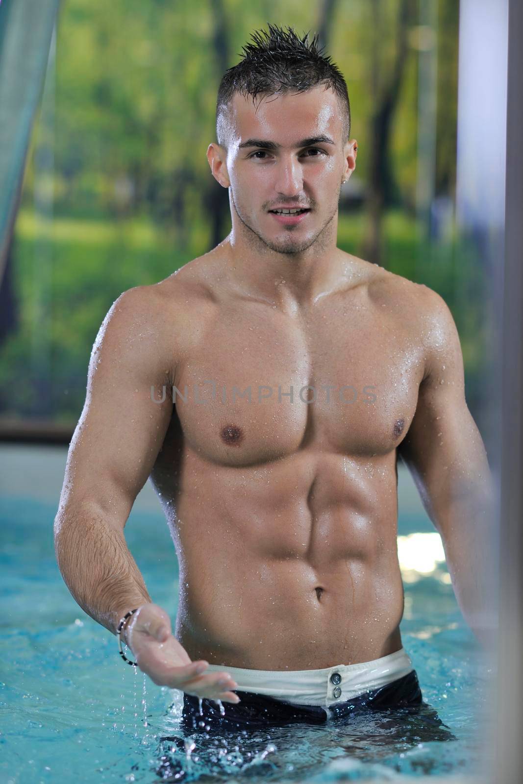 young healthy good looking macho man model athlete at hotel indoor pool