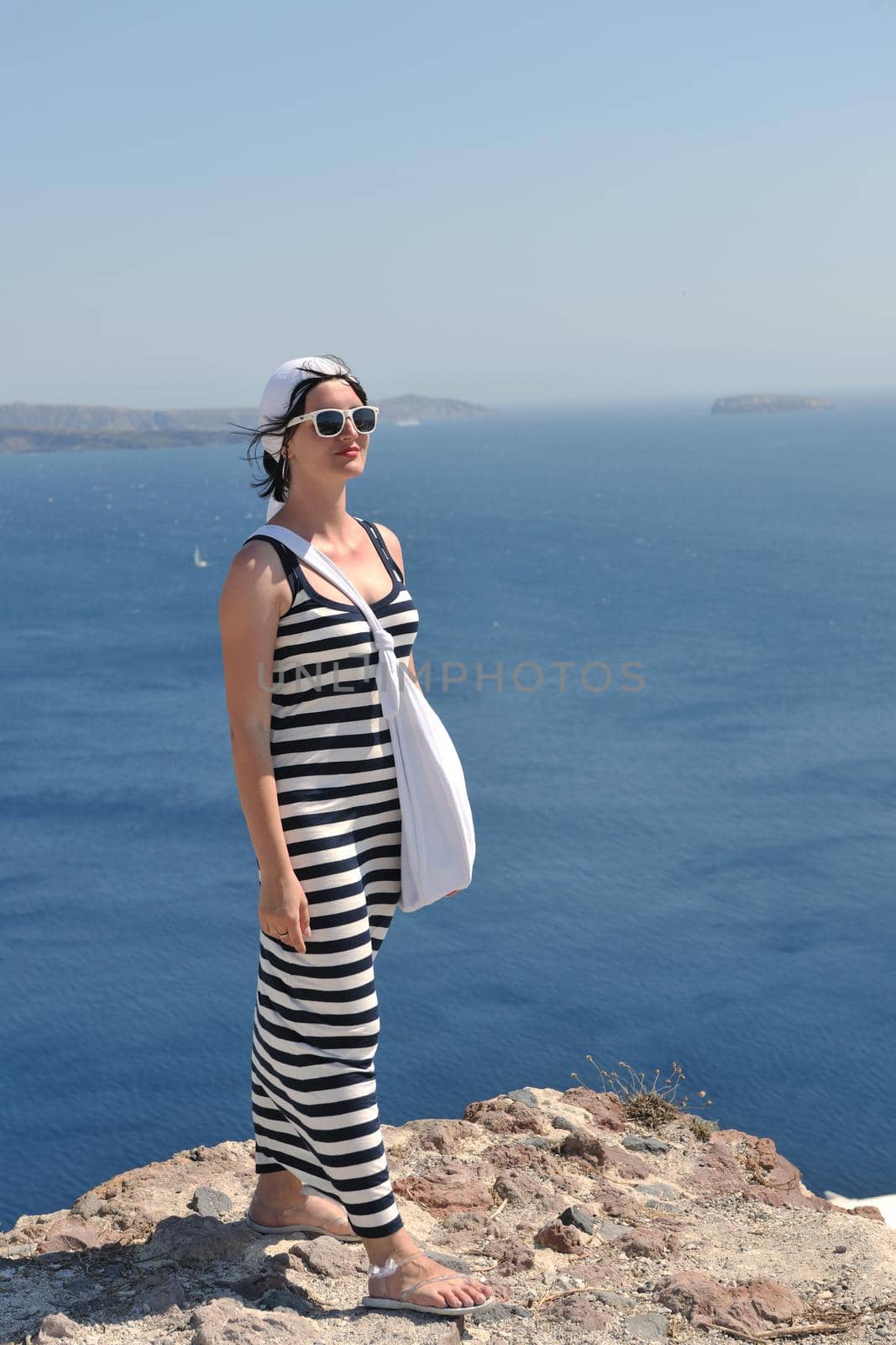 Beautiful young Greek woman in fashion clothes have fun at n the streets of Oia, Santorini, Greece