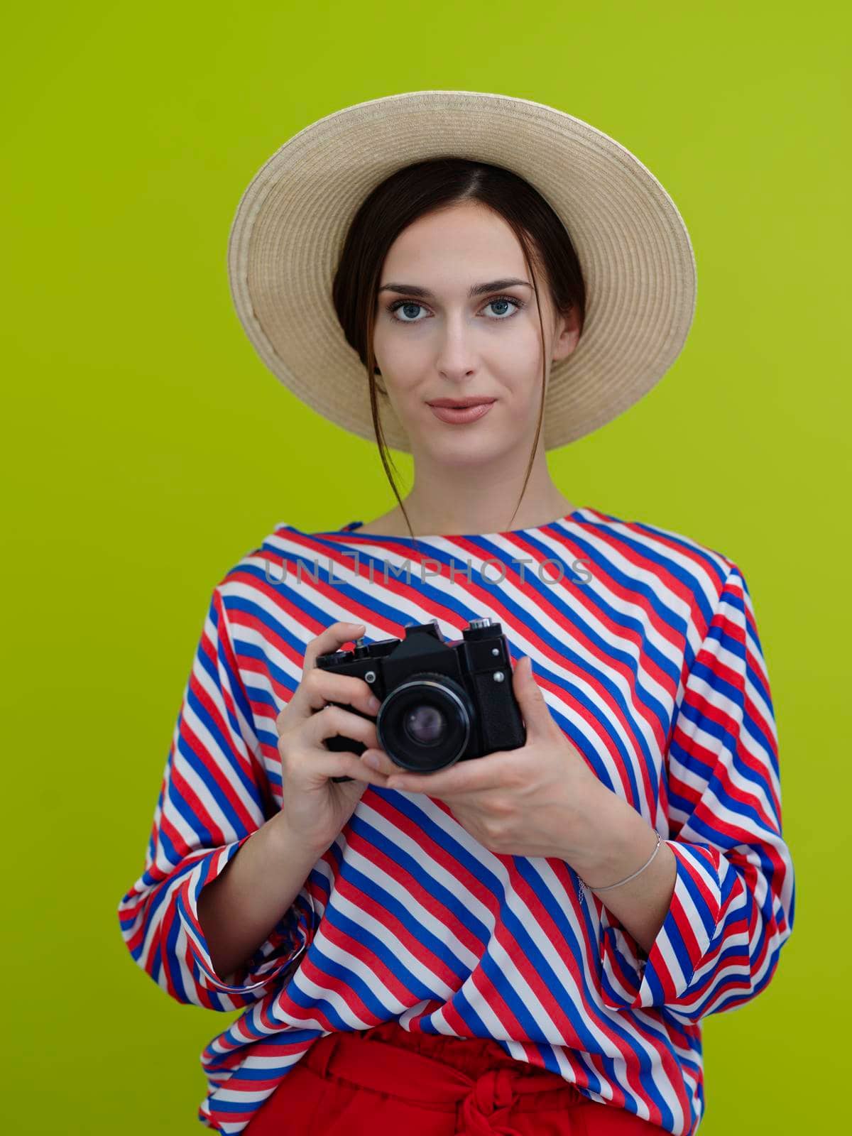 Portrait of beautiful female photographer close up. Say cheese. Young smiling woman holding camera and thinking how to make photo isolated on green background.