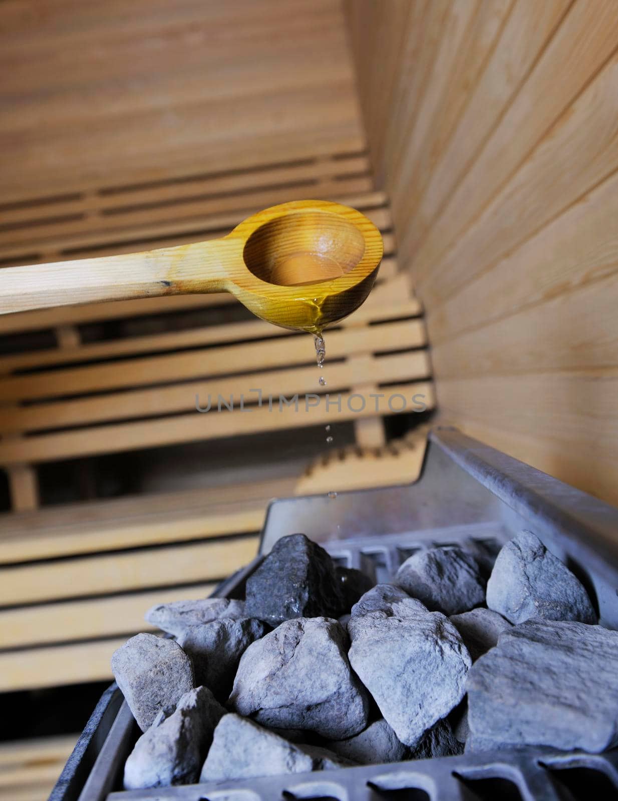 wooden luxury sauna indoor with hot stones and falling splashing water