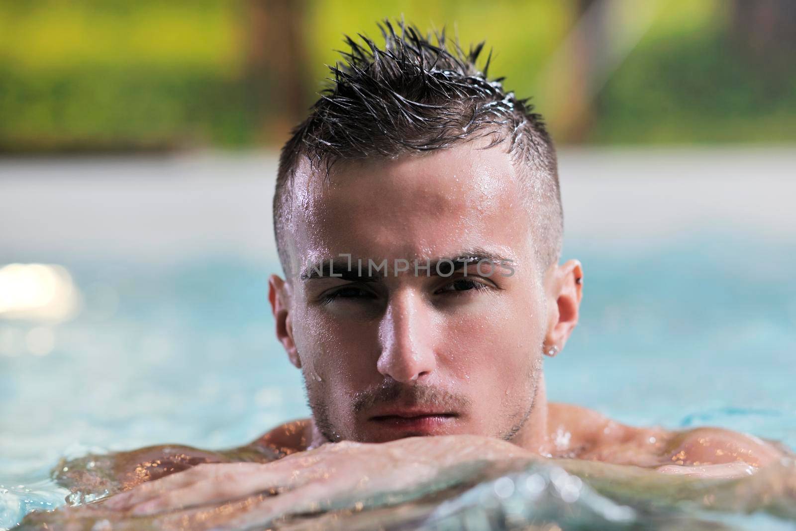 young healthy good looking macho man model athlete at hotel indoor pool