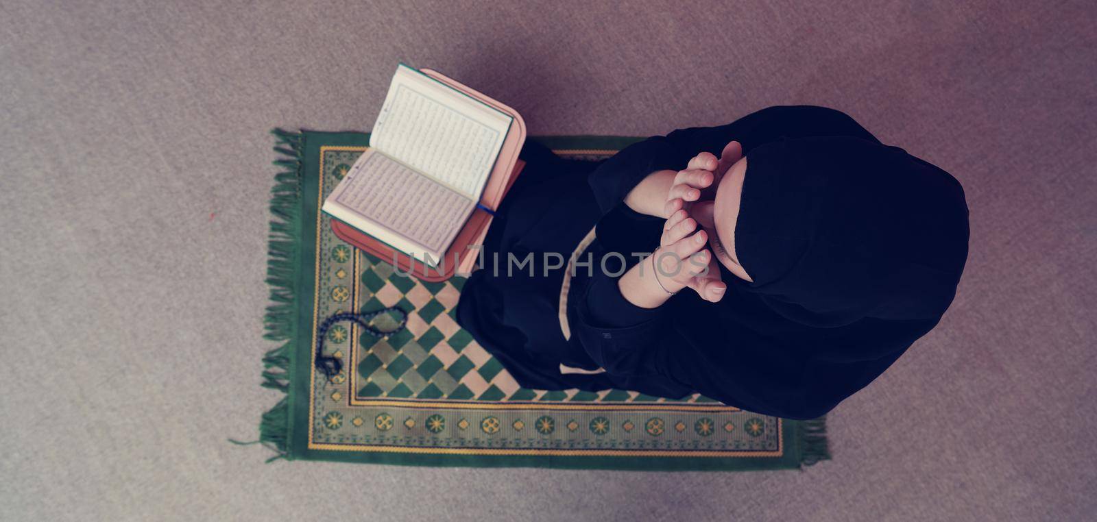 Middle eastern woman praying and reading the holy Quran (public item of all muslims). Education concept of Muslim woman studying The holy Quran at home or mosque in ramadan month.