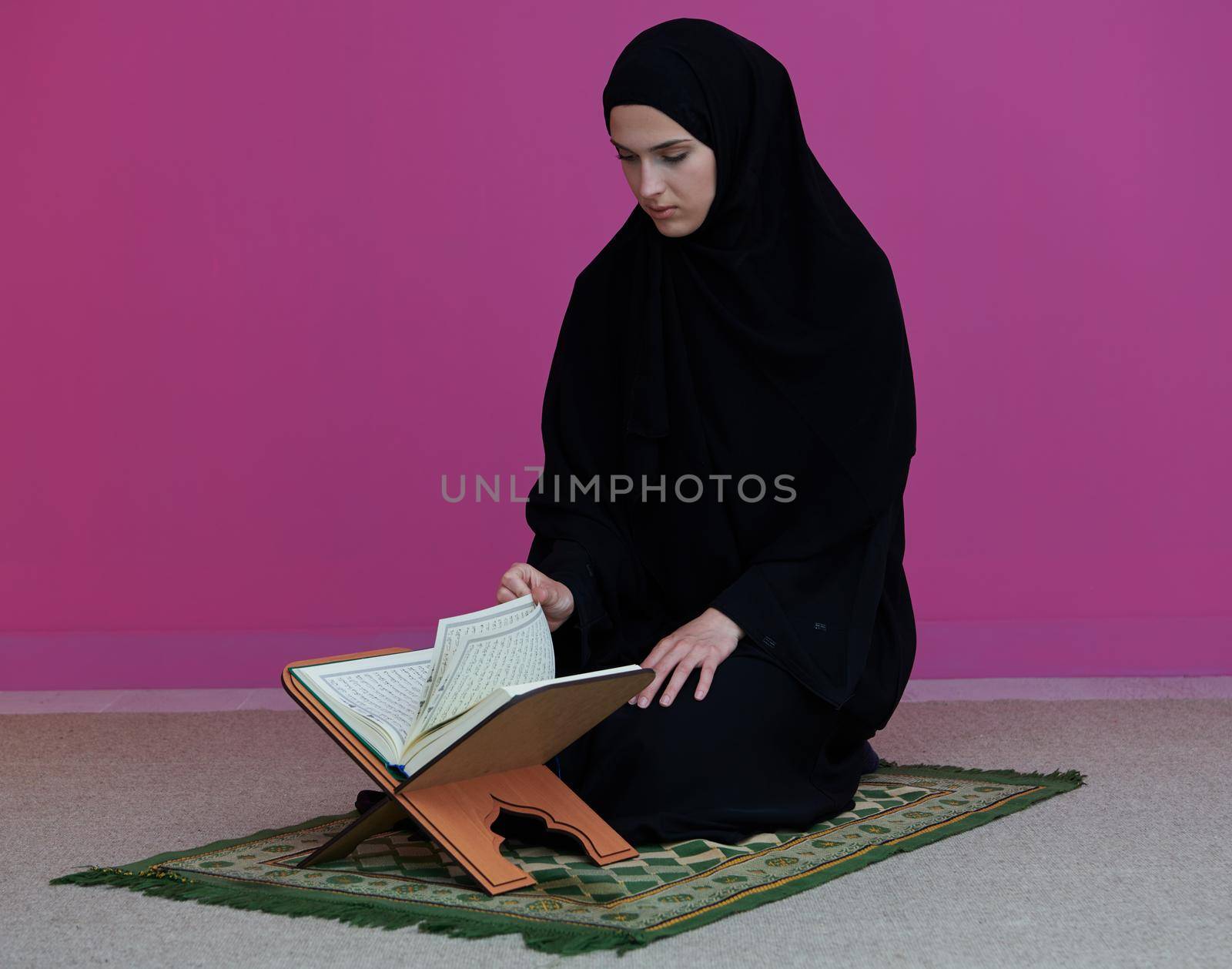 Sarajevo, Bosnia and Herzegovina - May 28, 2019 Middle eastern woman praying and reading the holy Quran (public item of all muslims). Education concept of Muslim woman studying The holy Quran at home or mosque in ramadan month.