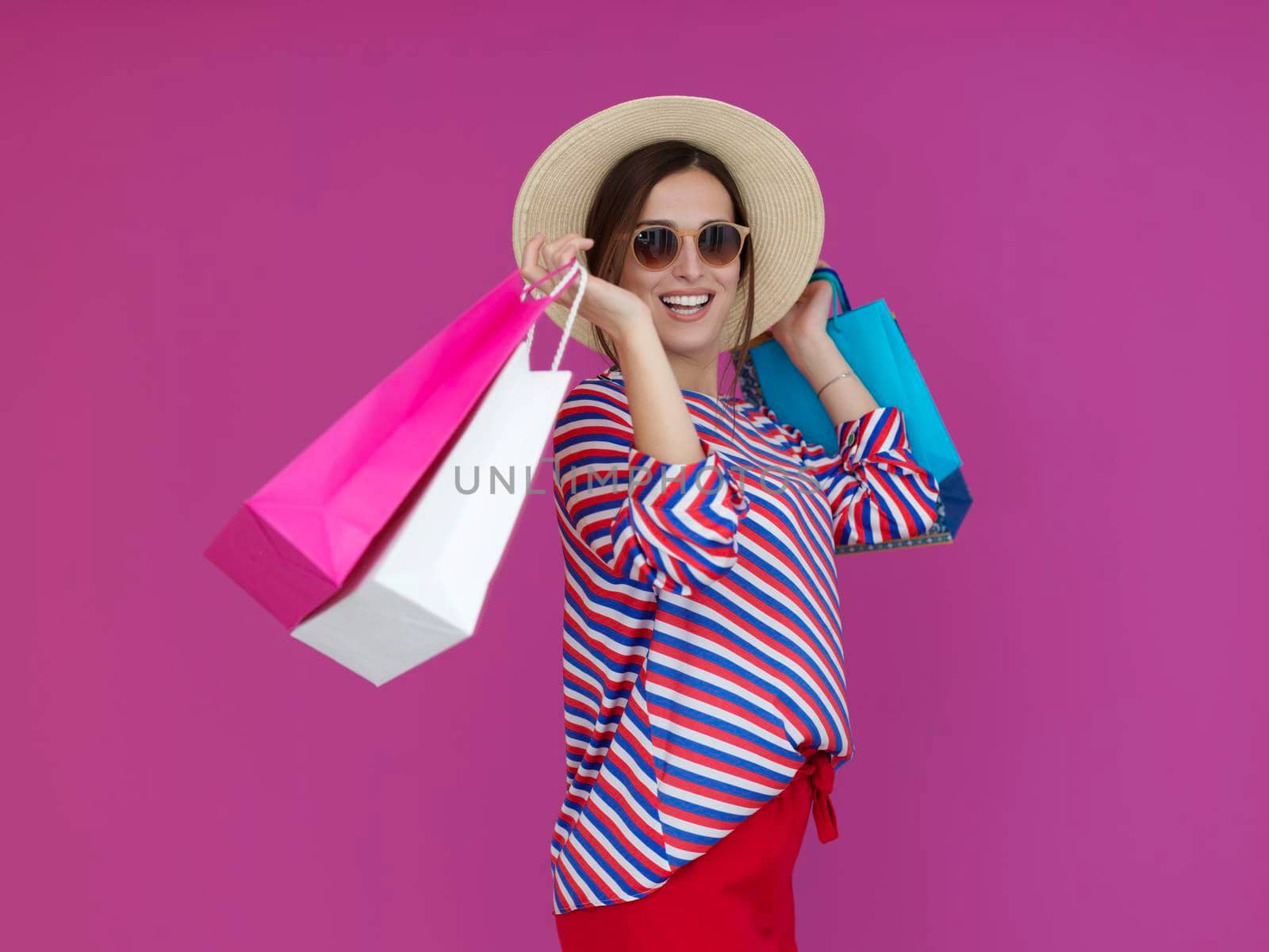 Young woman with shopping bags on pink background. Happy girl posing with new purchases after a day of big sale. Black Friday concept