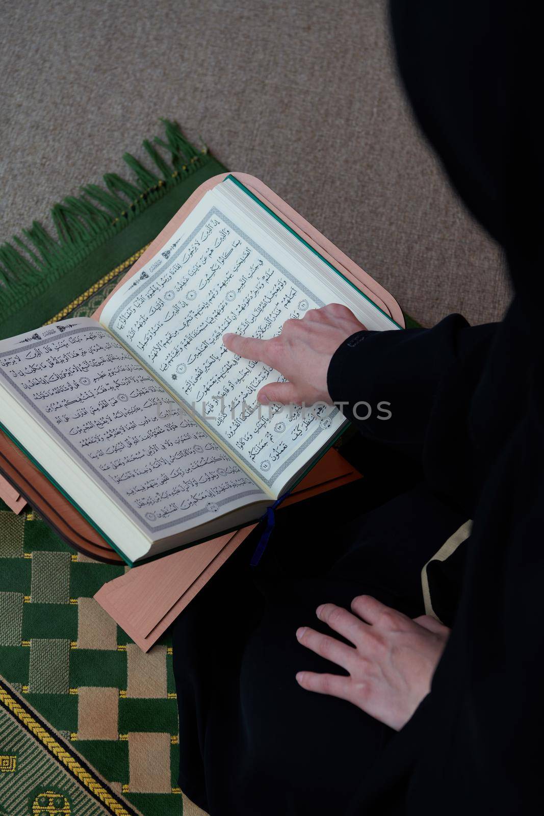 Sarajevo, Bosnia and Herzegovina - May 28, 2019 Middle eastern woman praying and reading the holy Quran (public item of all muslims). Education concept of Muslim woman studying The holy Quran at home or mosque in ramadan month.