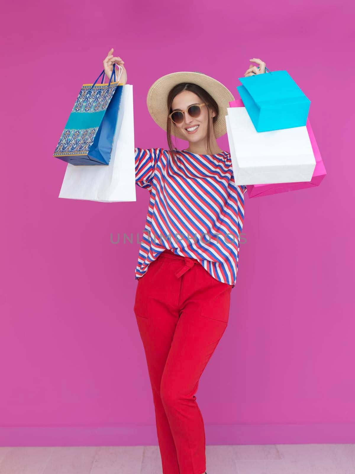 Young woman with shopping bags on pink background. Happy girl posing with new purchases after a day of big sale. Black Friday concept