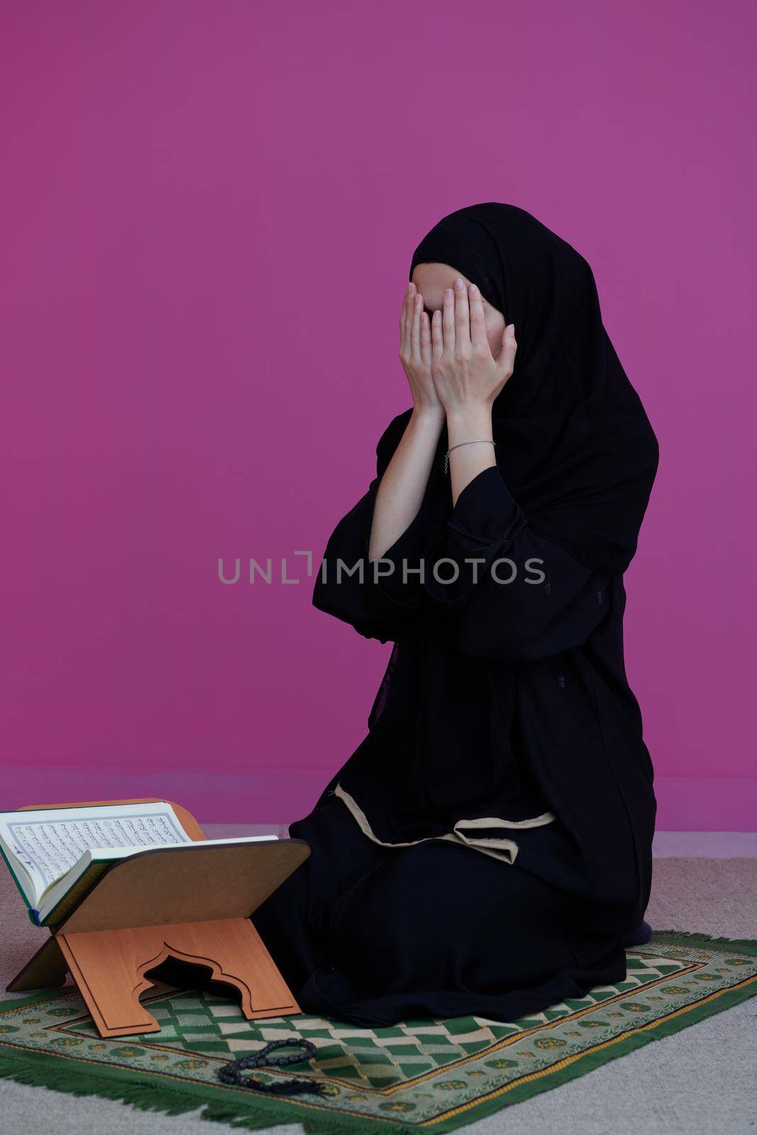 Sarajevo, Bosnia and Herzegovina - May 28, 2019 Middle eastern woman praying and reading the holy Quran (public item of all muslims). Education concept of Muslim woman studying The holy Quran at home or mosque in ramadan month.