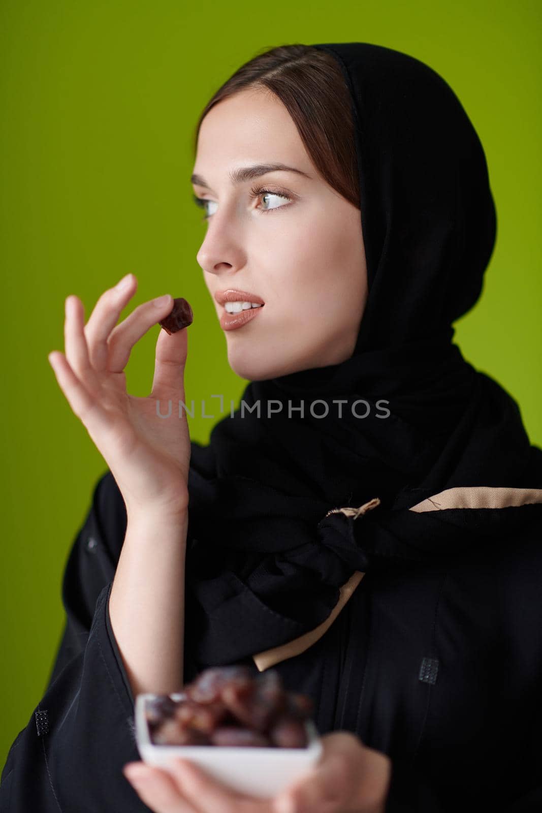 Woman in Abaya Holding a Date Fruit and glass of water by dotshock