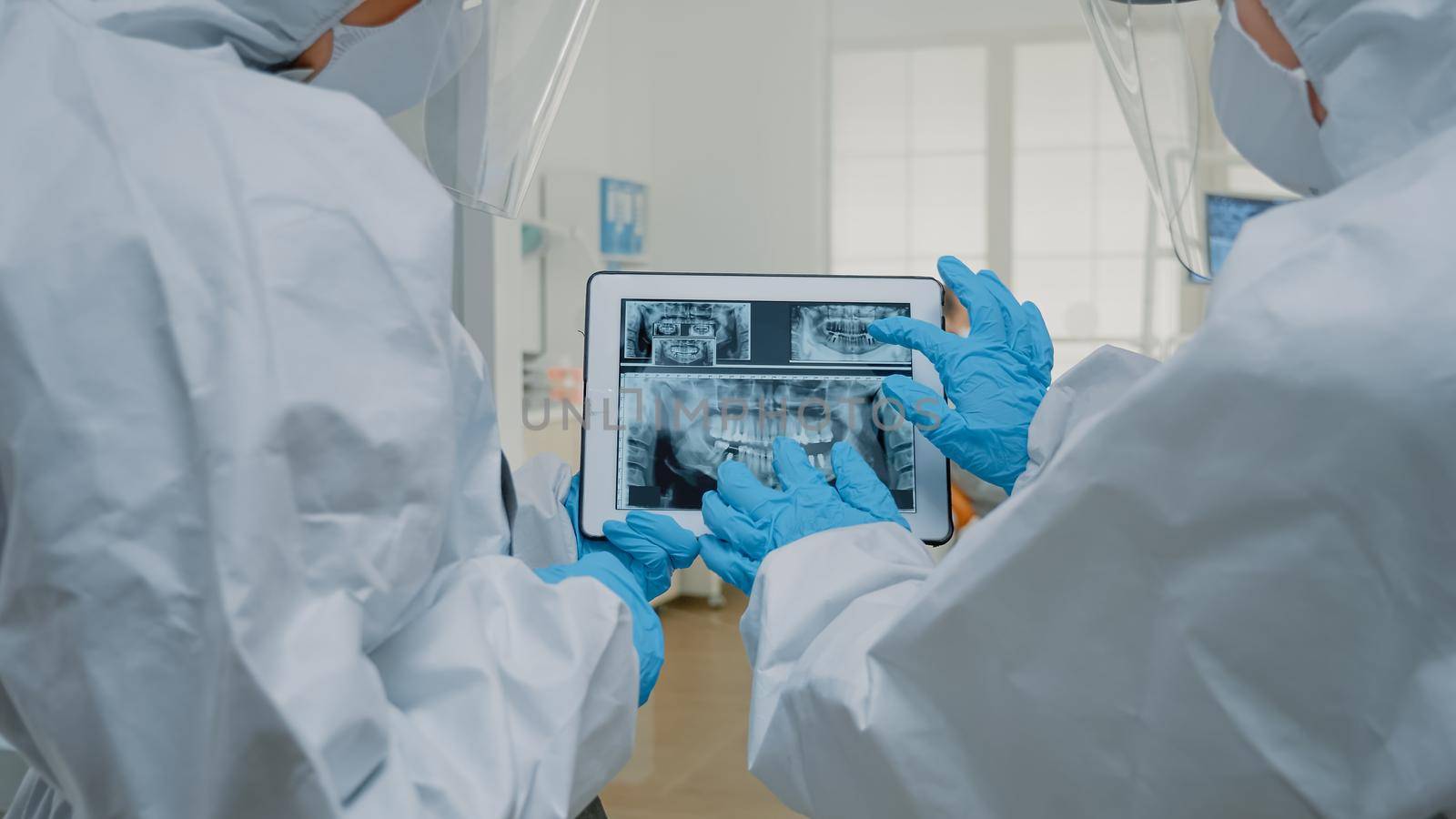 Dental doctors examining x ray of teeth on tablet screen by DCStudio