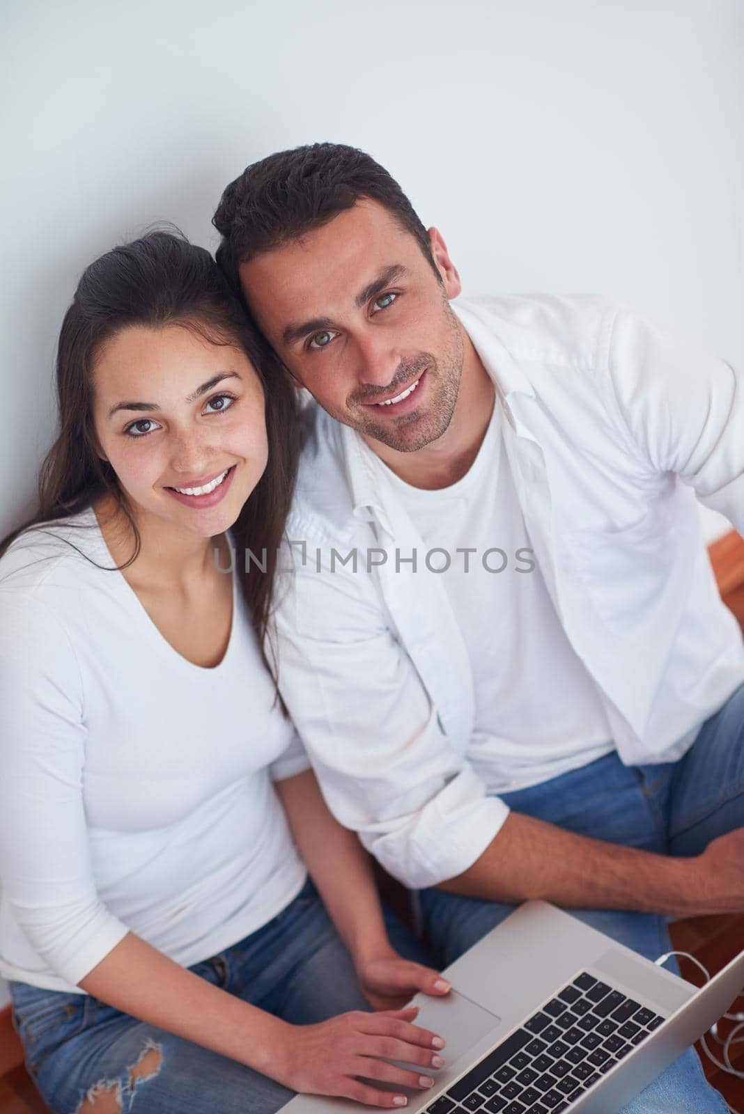 happy young relaxed  couple working on laptop computer at modern home interior