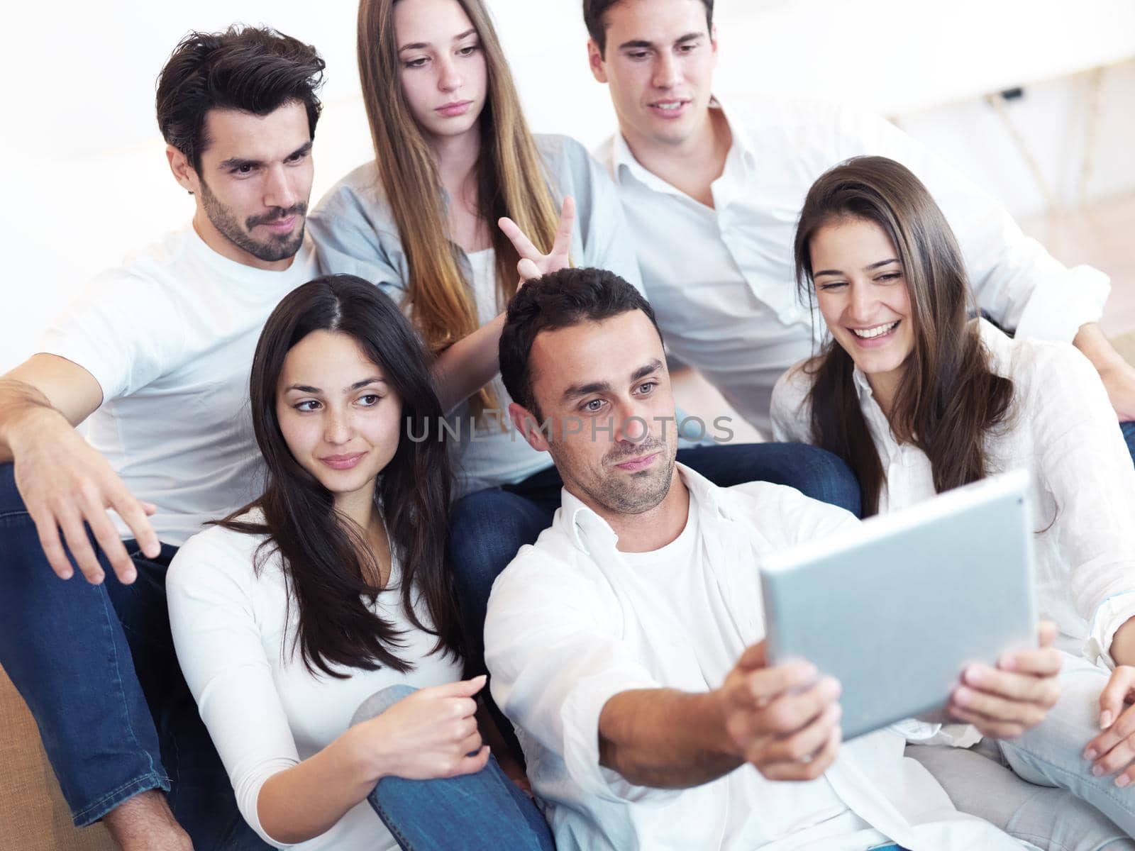 group of friends taking selfie photo with tablet at modern home indoors