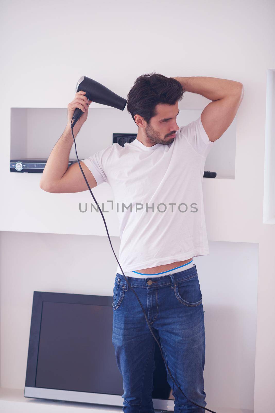 young handsome nude man at home using  hair  hairdryer