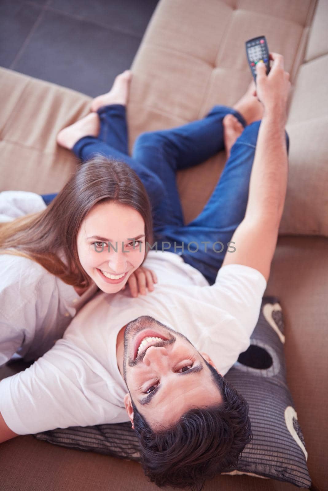 Relaxed young couple watching tv at home in bright living room