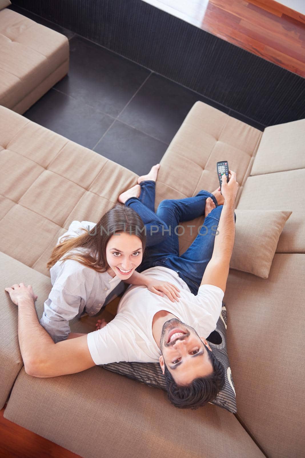 Relaxed young couple watching tv at home in bright living room