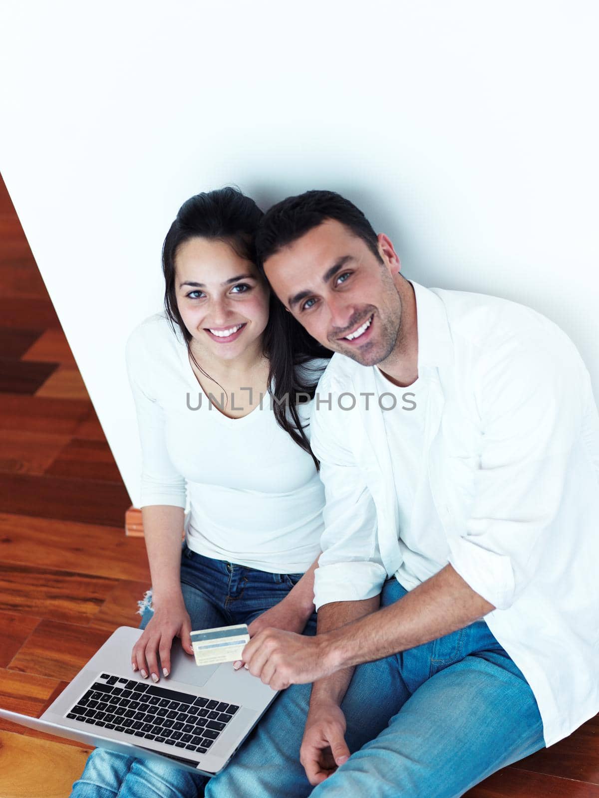happy young relaxed  couple working on laptop computer at modern home interior
