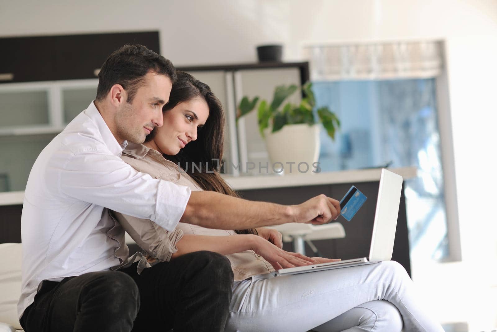 joyful couple relax and work on laptop computer at modern living room indoor home