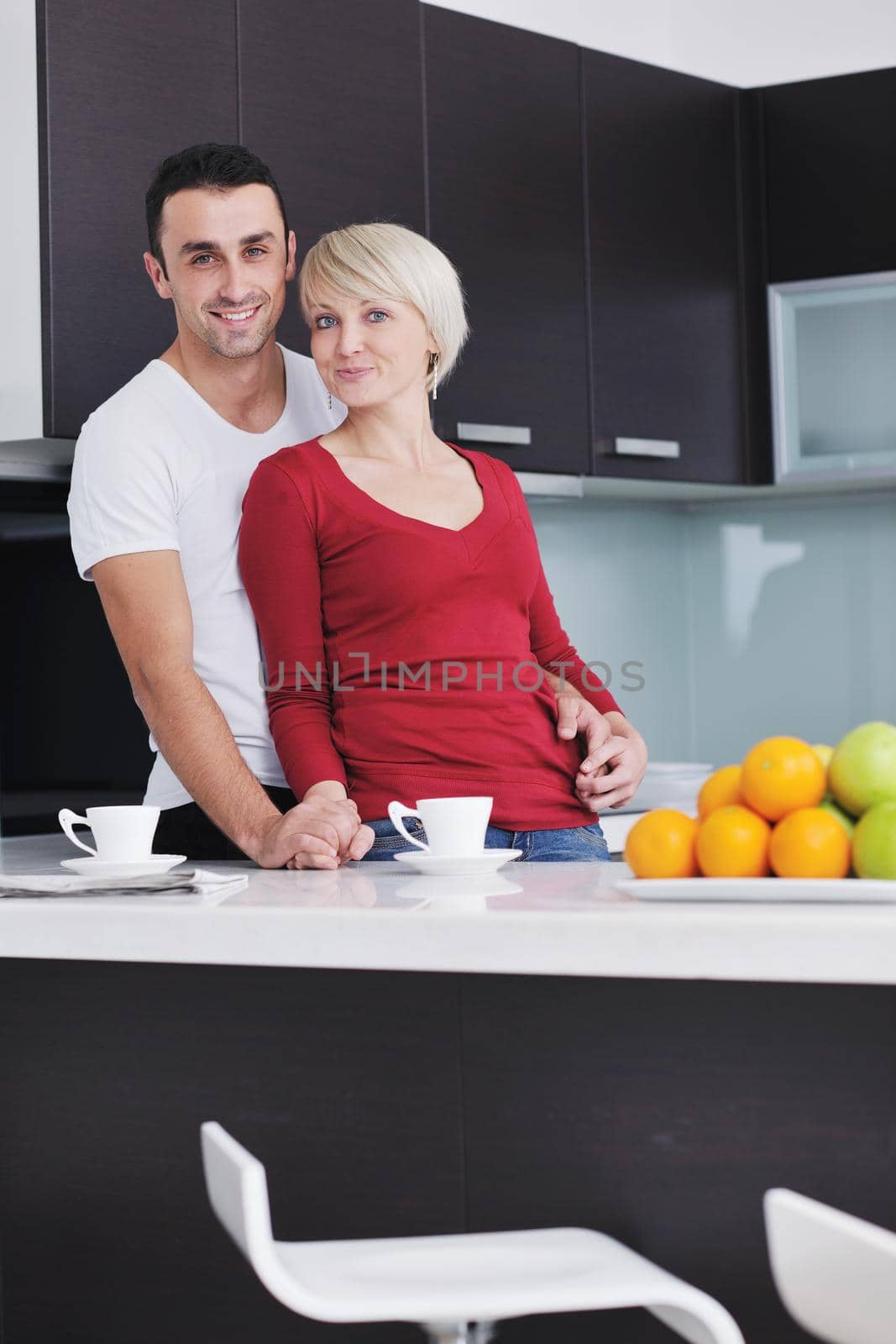 happy young couple have fun in  modern kitchen indoor  while preparing fresh fruits and vegetables food salad