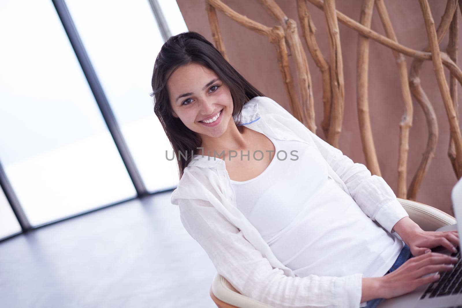 beautiful young woman relax and work on laptop computer modern  home office while listening musin on white headphones