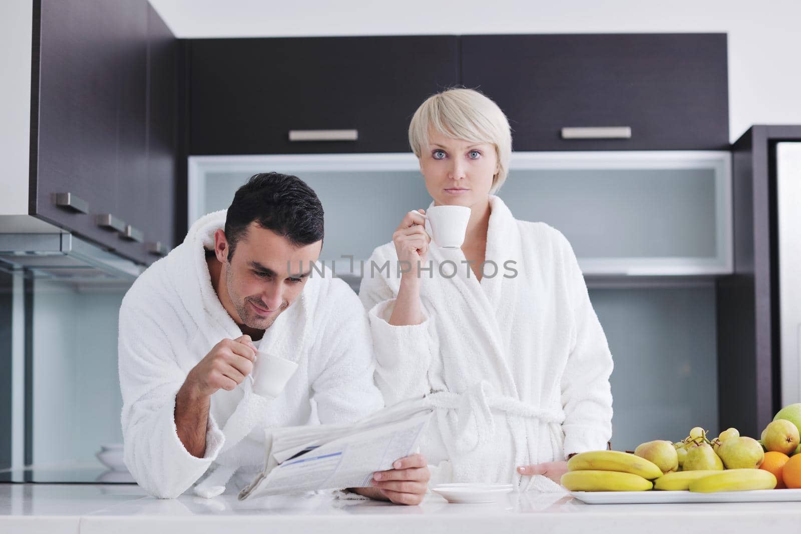 Happy couple reading the newspaper in the kitchen at breakfast by dotshock