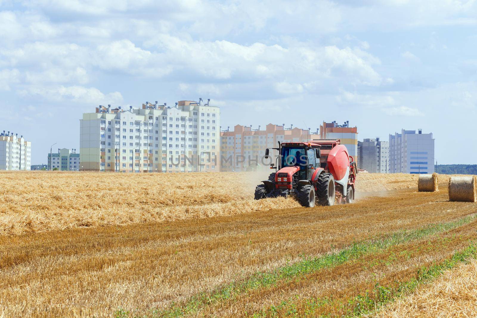 A round baler discharges a fresh wheat bale during harvesting.