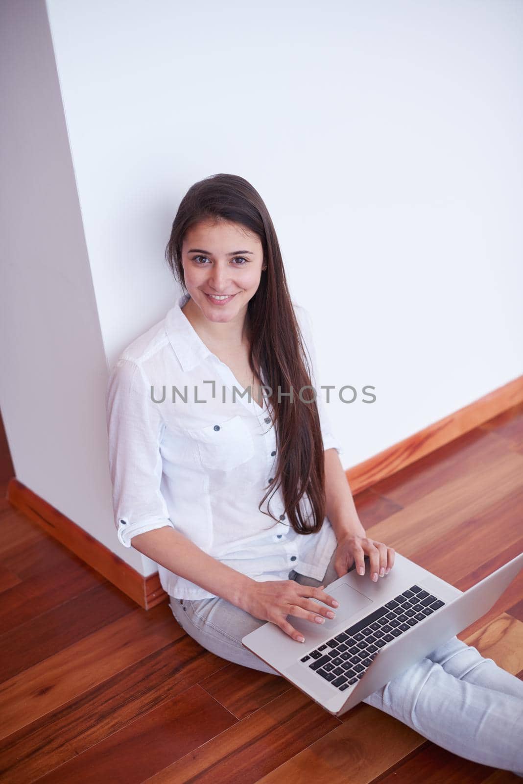relaxed young woman at home working on laptop computer by dotshock