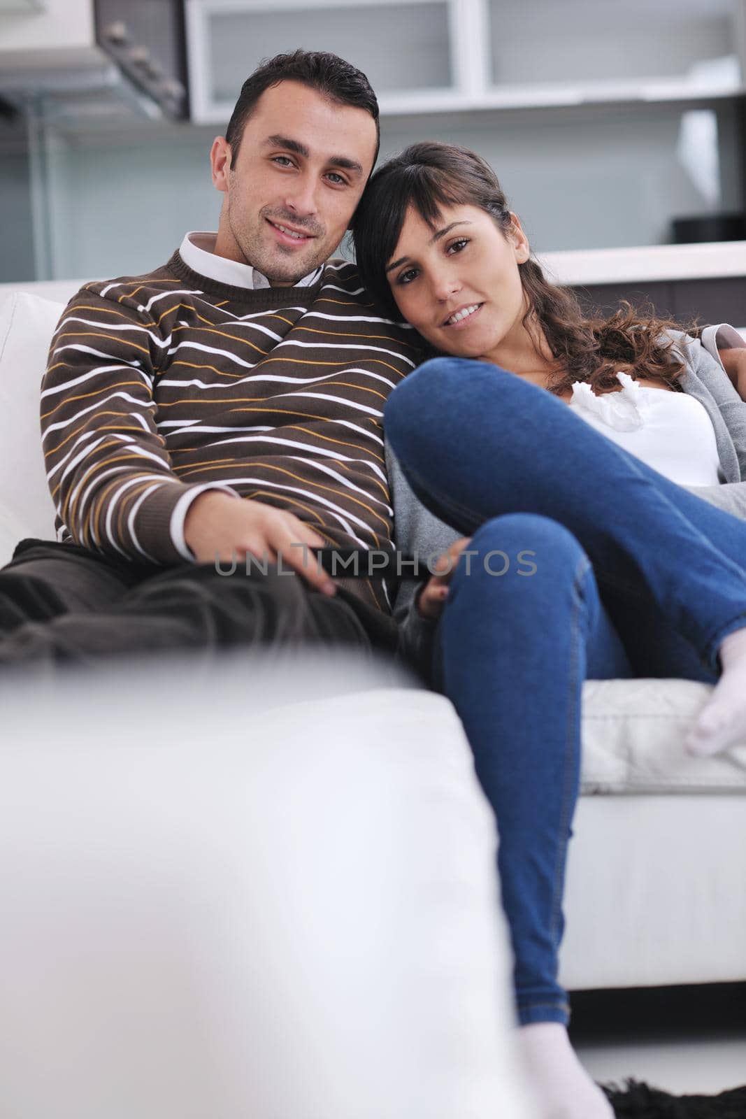 Relaxed young  couple watching tv at home in bright living room