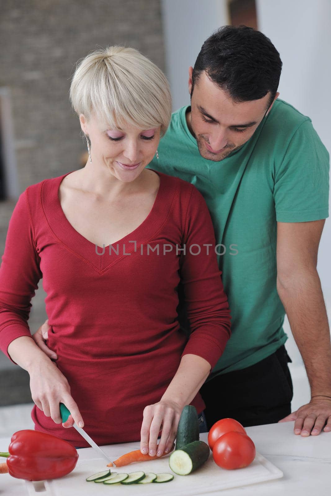 happy young couple have fun in  modern kitchen indoor  while preparing fresh fruits and vegetables food salad