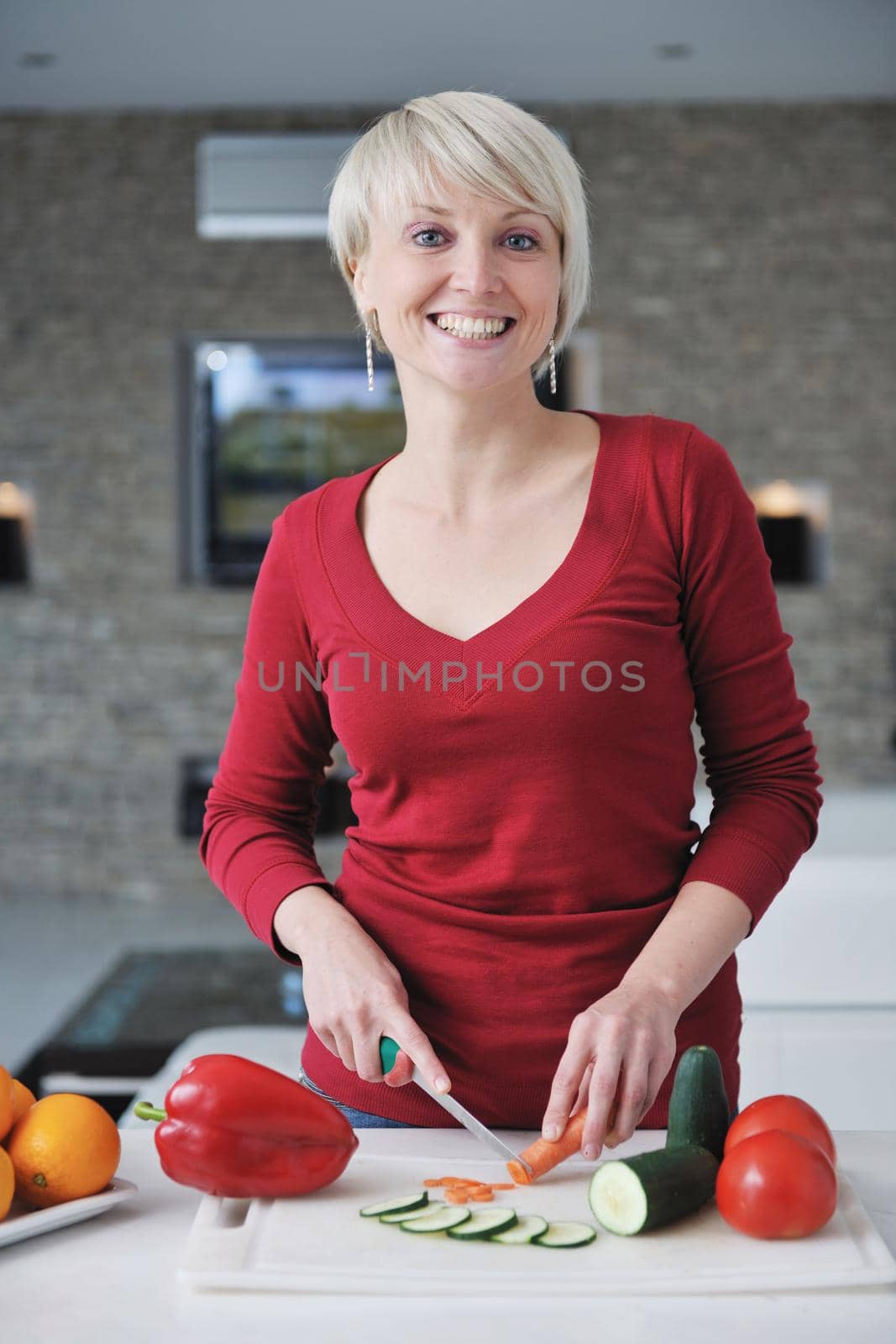 happy young  beautiful blonde  woman prepare food in  the kitchen at home
