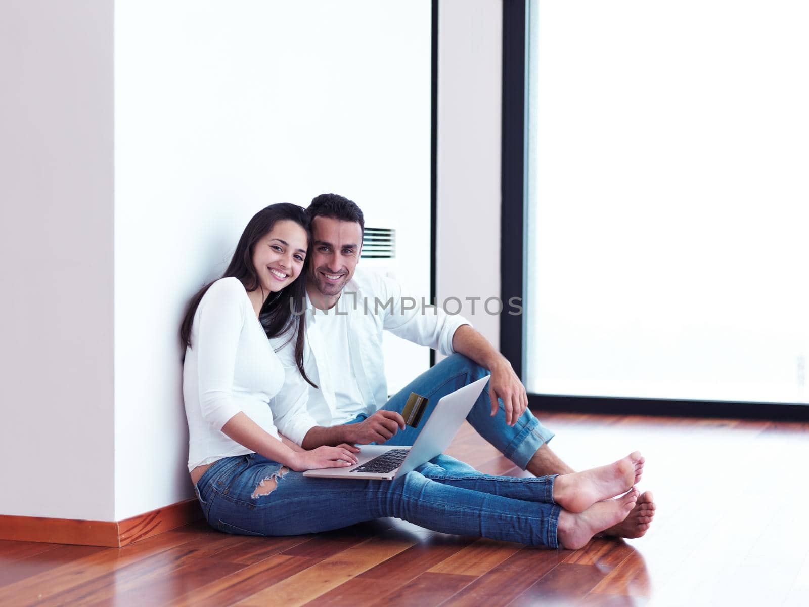 happy young relaxed  couple working on laptop computer at modern home interior