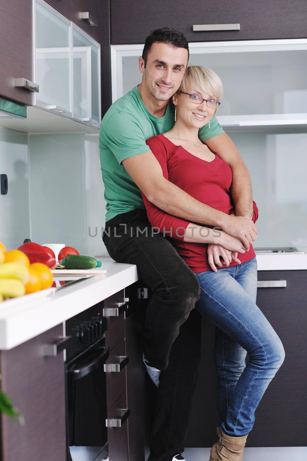 happy young couple have fun in  modern kitchen indoor  while preparing fresh fruits and vegetables food salad