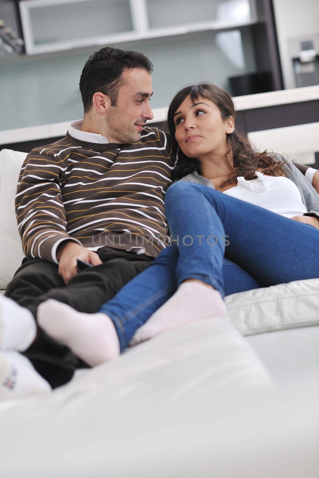 Relaxed young  couple watching tv at home in bright living room