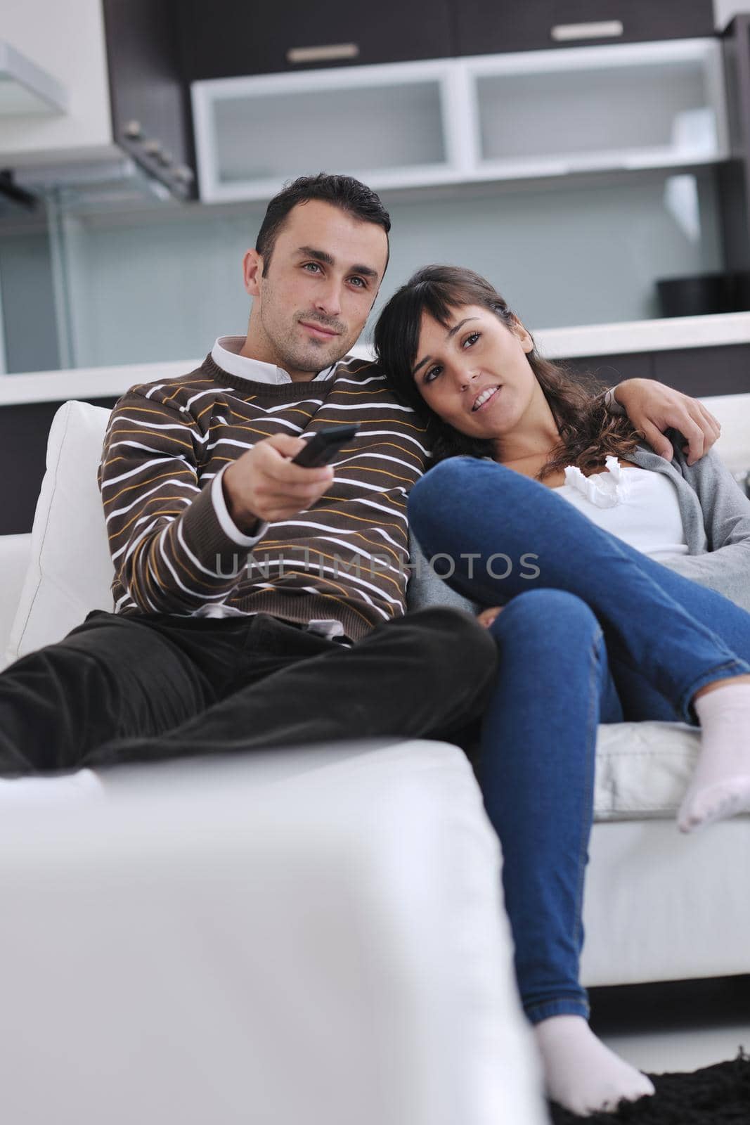 Relaxed young  couple watching tv at home in bright living room