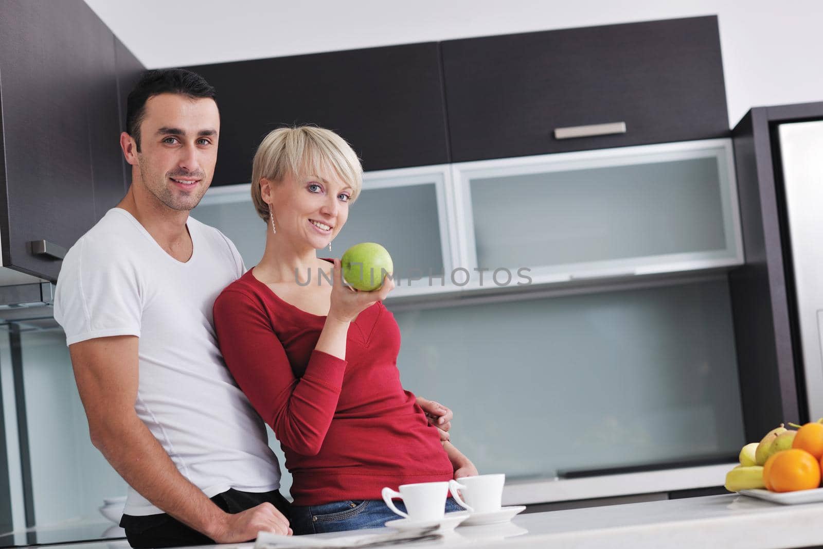 happy young couple have fun in  modern kitchen indoor  while preparing fresh fruits and vegetables food salad