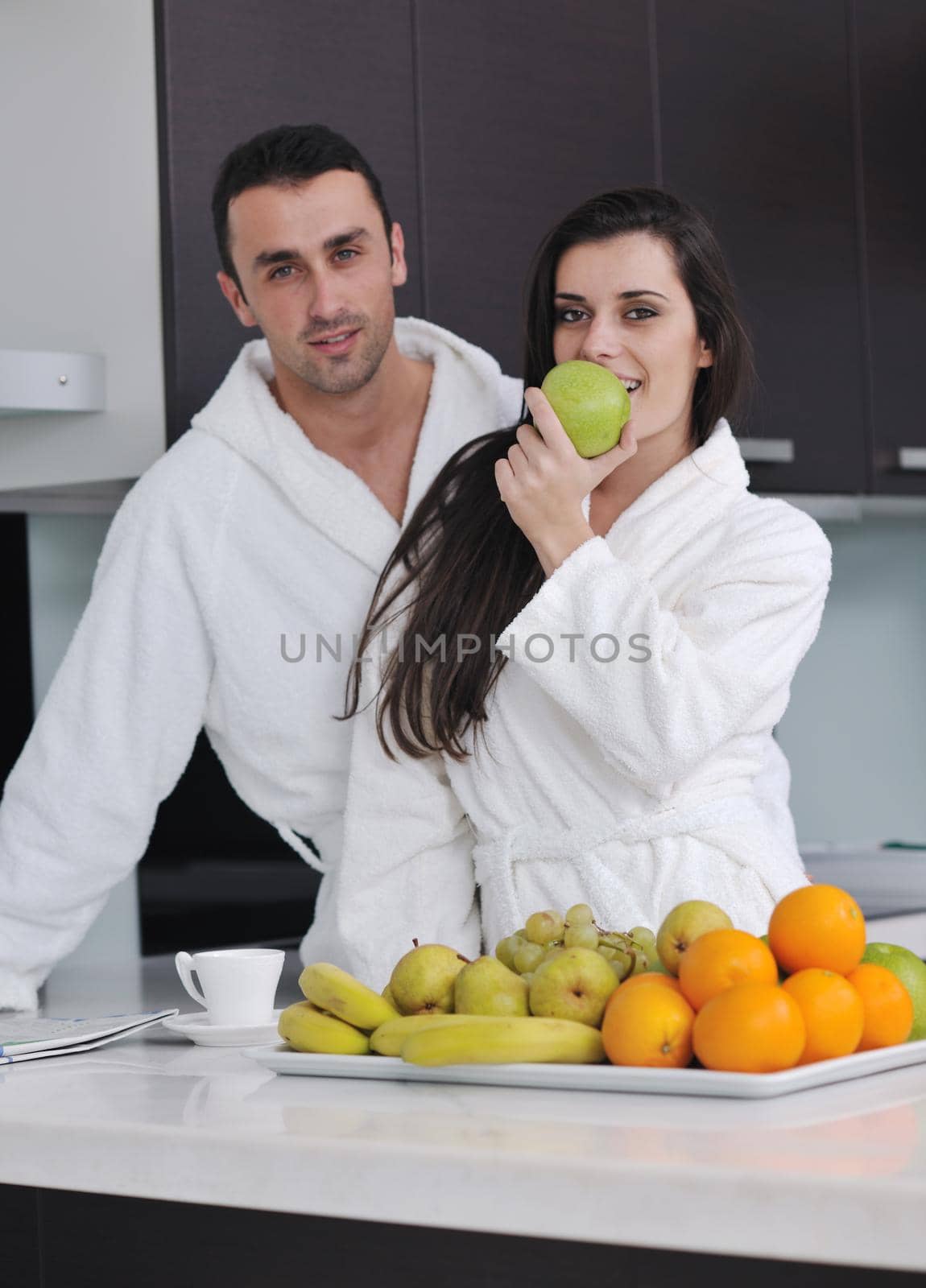 happy young couple have fun in  modern kitchen indoor  while preparing fresh fruits and vegetables food salad