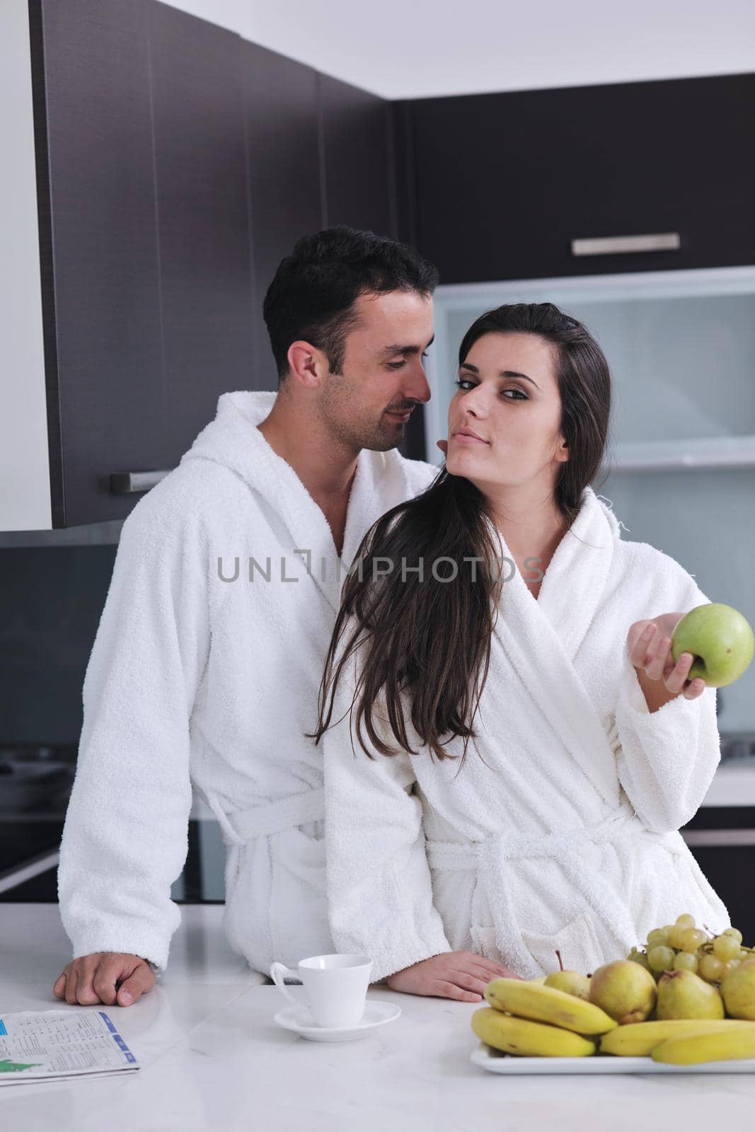 happy young couple have fun in  modern kitchen indoor  while preparing fresh fruits and vegetables food salad