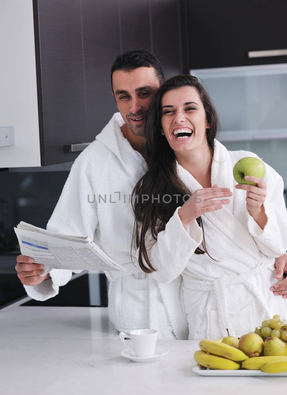 happy young couple have fun in  modern kitchen indoor  while preparing fresh fruits and vegetables food salad