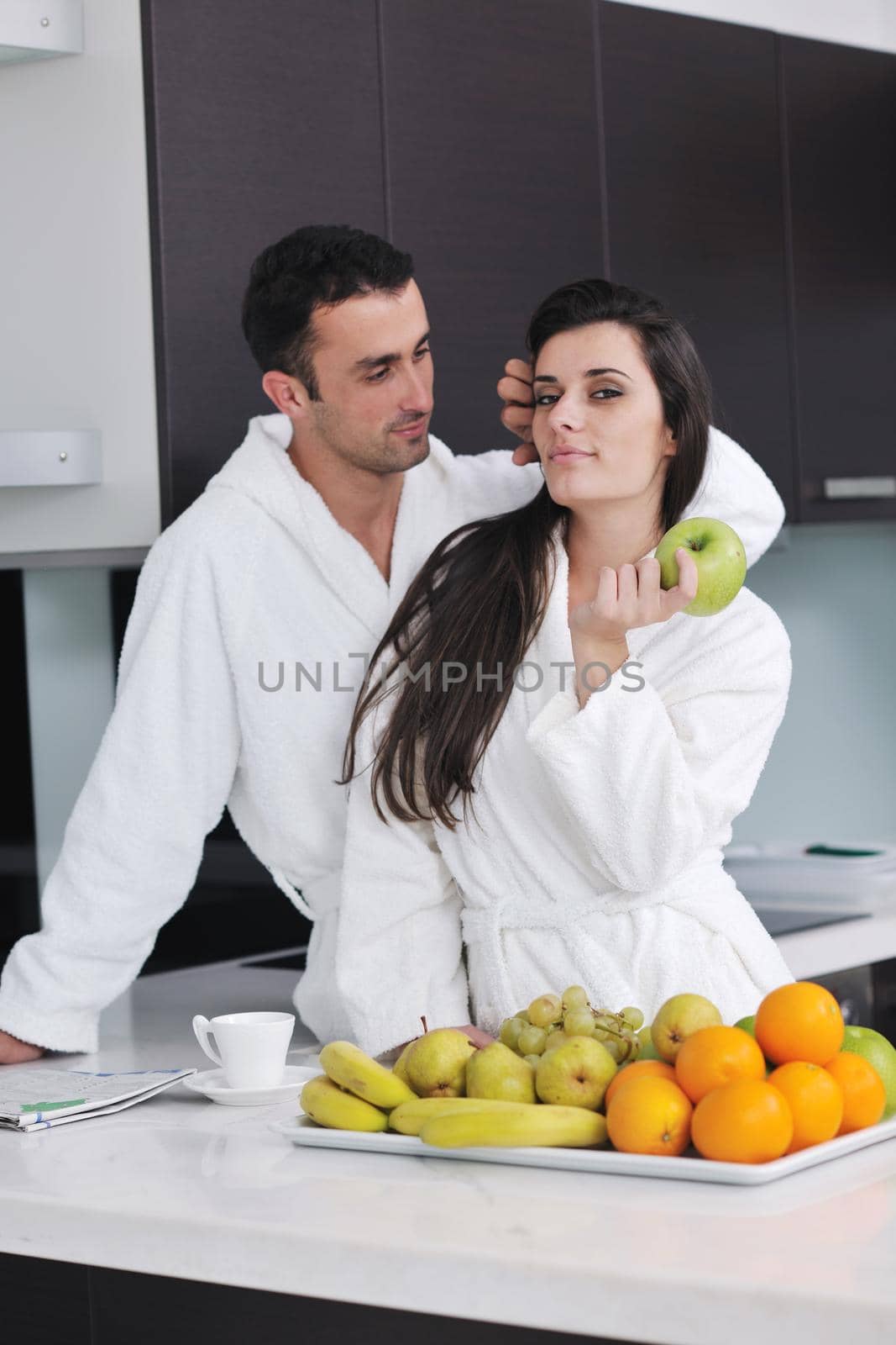 happy young couple have fun in  modern kitchen indoor  while preparing fresh fruits and vegetables food salad