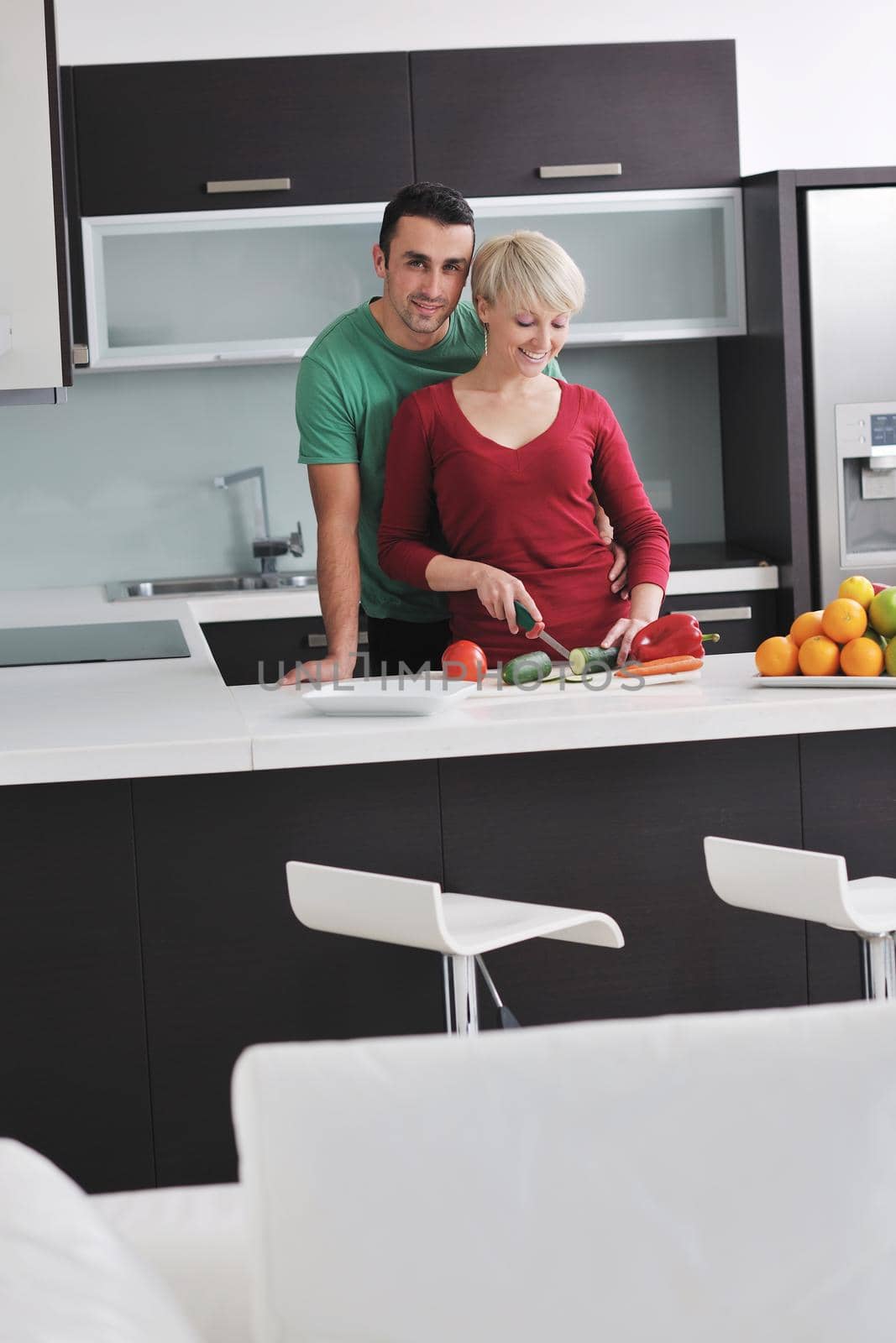 happy young couple have fun in  modern kitchen indoor  while preparing fresh fruits and vegetables food salad