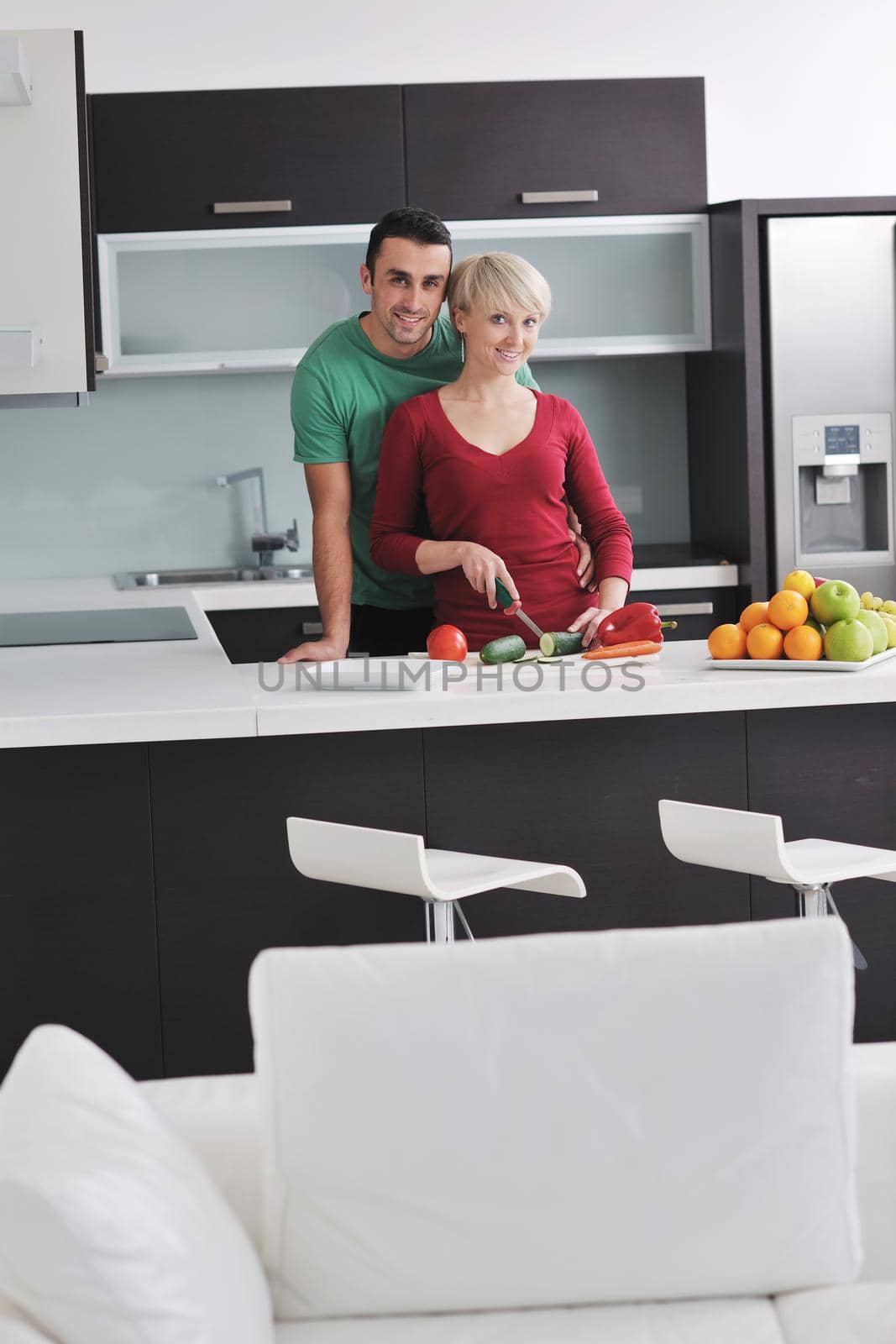 happy young couple have fun in  modern kitchen indoor  while preparing fresh fruits and vegetables food salad