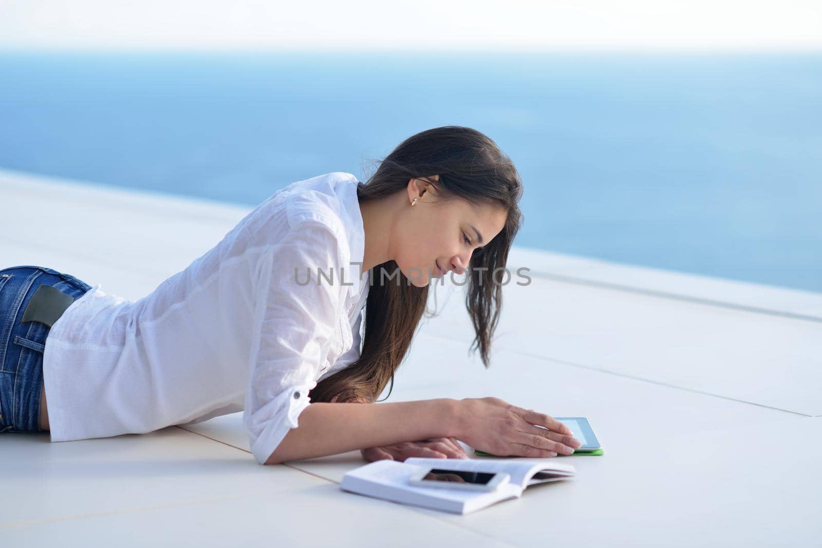 beautiful young woman relax and work on laptop computer while listening music on heaphones and read book at home