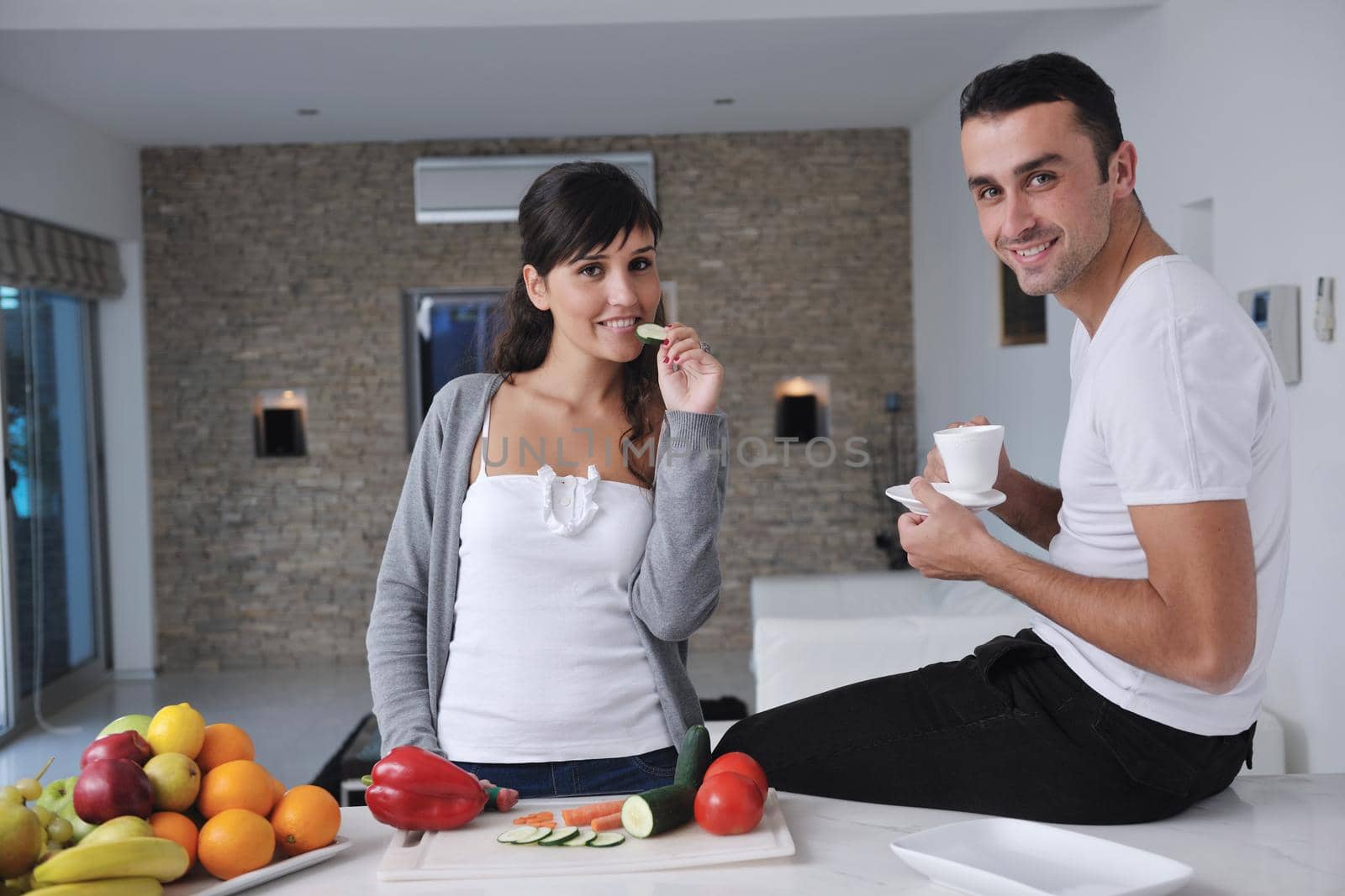 happy young couple have fun in  modern kitchen indoor  while preparing fresh fruits and vegetables food salad