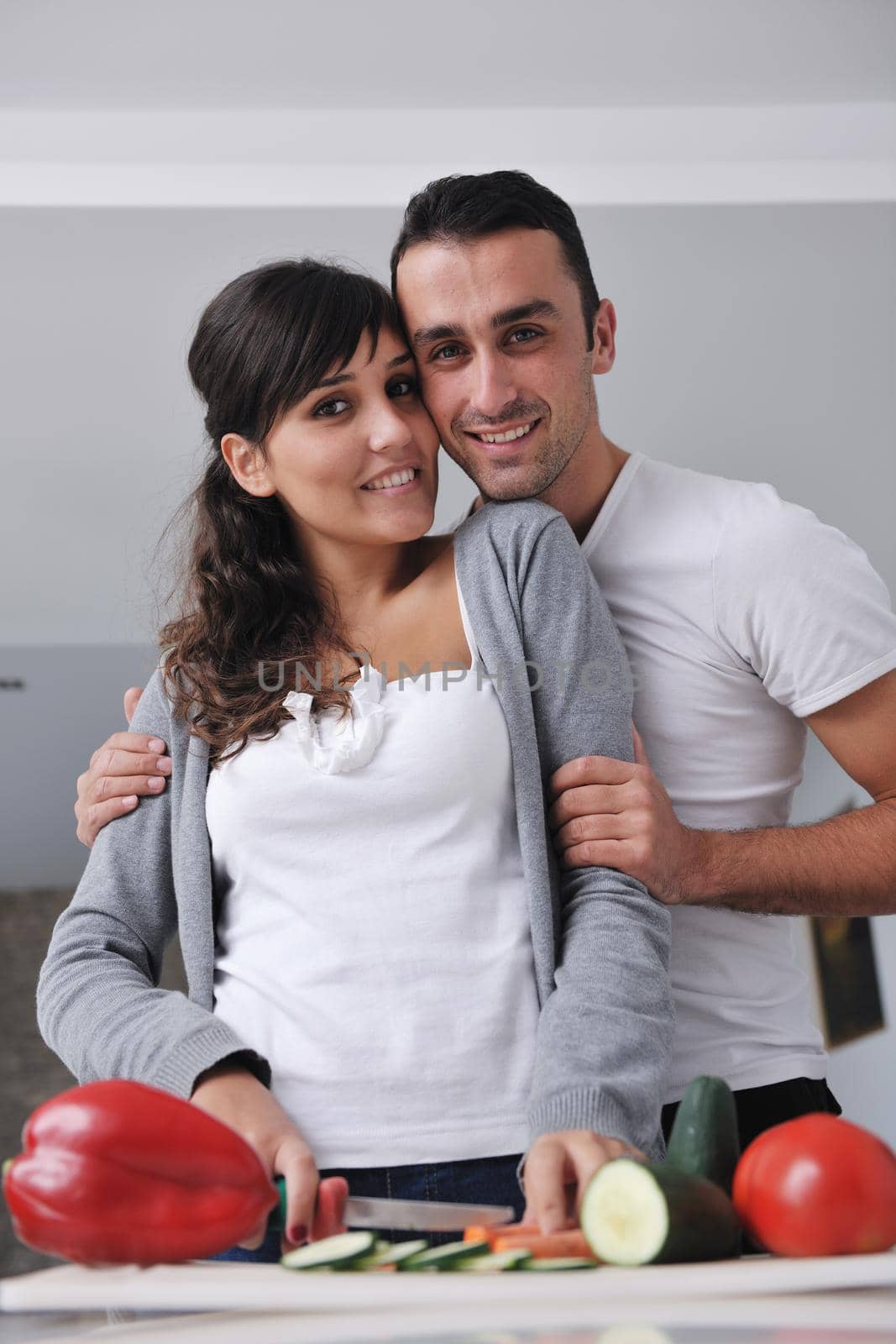 happy young couple have fun in  modern kitchen indoor  while preparing fresh fruits and vegetables food salad