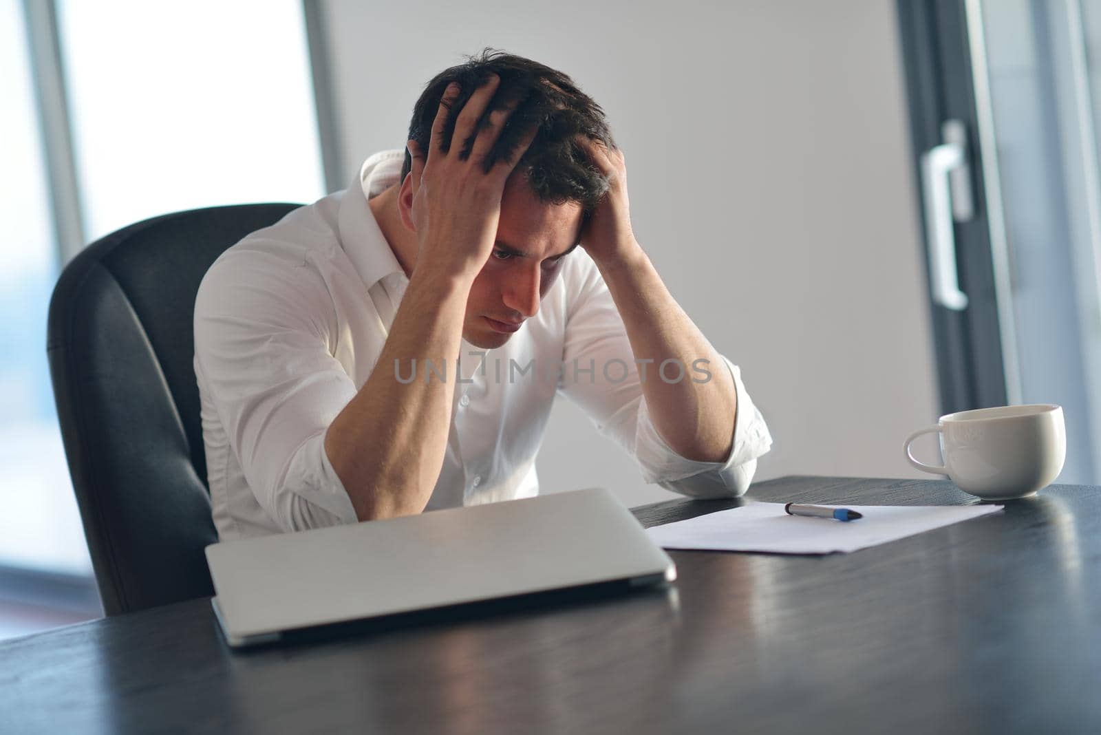 frustrated young business man working on laptop computer at home by dotshock