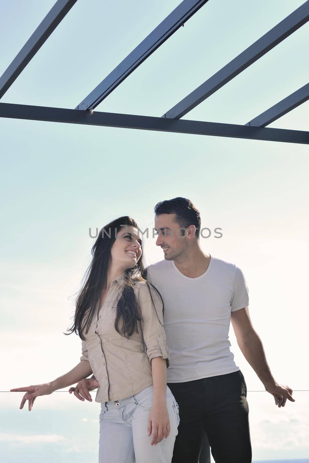 happy young couple relax on balcony outdoor with ocean and blue sky in background