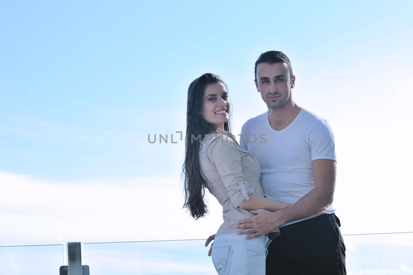 happy young couple relax on balcony outdoor with ocean and blue sky in background